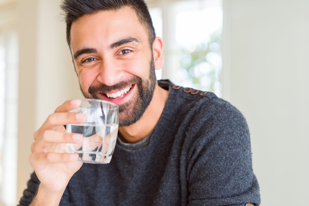 Man drinking alkaline water from glass